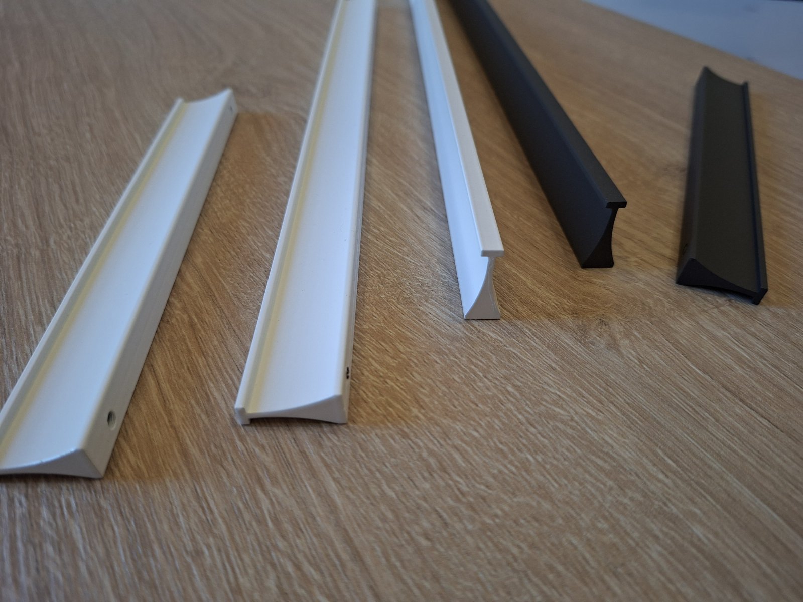 Modern Inka anthracite furniture handles and matte white wardrobe pulls. Luxury aluminium hardware from Stillium, shipping to custom kitchen designers in Switzerland, Austria, Croatia, and Slovenia.